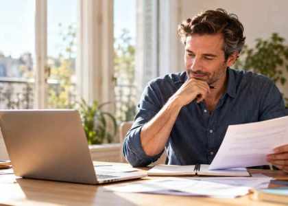Freelance consultant comparant son ordinateur et son bulletin de paie dans un bureau lumineux.